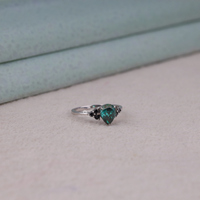 Pear cut green moissanite accent stone engagement ring with round black side stones in a prong setting