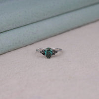 Pear cut green moissanite accent stone engagement ring with round black side stones in a prong setting
