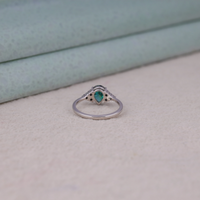 Pear cut green moissanite accent stone engagement ring with round black side stones in a prong setting