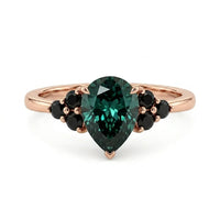 metalcolor:rose Pear cut green moissanite accent stone engagement ring with round black side stones in a prong setting