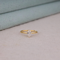 Pear cut moissanite solitaire engagement ring with clear center stone in prong setting and minimalist band design