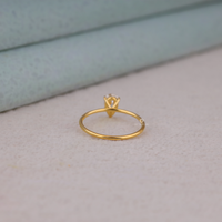 Pear cut moissanite solitaire engagement ring with clear center stone in prong setting and minimalist band design