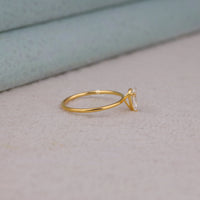 Pear cut moissanite solitaire engagement ring with clear center stone in prong setting and minimalist band design