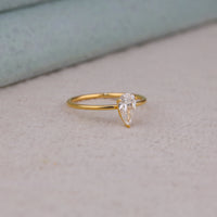 Pear cut moissanite solitaire engagement ring with clear center stone in prong setting and minimalist band design