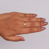 Pear cut moissanite solitaire engagement ring with clear center stone in prong setting and minimalist band design