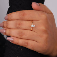 Pear cut moissanite solitaire engagement ring with clear center stone in prong setting and minimalist band design