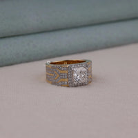 Men's princess cut Moissanite halo ring with wide geometric pavé band and statement luxury design in yellow tone metal.