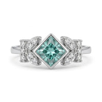 Princess cut moissanite engagement ring with aqua green center stone, leaf accent side stones, and nature-inspired design