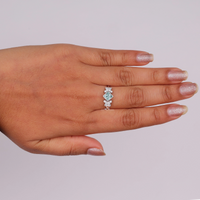 Princess cut moissanite engagement ring with aqua green center stone, leaf accent side stones, and nature-inspired design