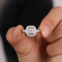 Silver ring with diamonds held between fingers against a neutral background