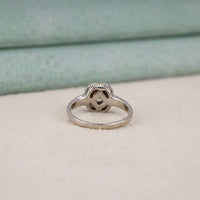 Silver ring with a diamond on a light beige surface with a greenish background