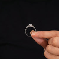Hand holding a diamond ring against a black background