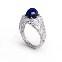 Vintage filigree statement ring featuring deep blue cabochon center stone with round accent stones and intricate scrollwork design