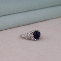 Vintage filigree statement ring featuring deep blue cabochon center stone with round accent stones and intricate scrollwork design