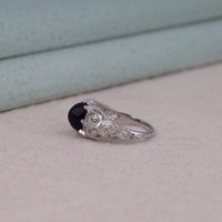 Vintage filigree statement ring featuring deep blue cabochon center stone with round accent stones and intricate scrollwork design