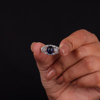 Vintage filigree statement ring featuring deep blue cabochon center stone with round accent stones and intricate scrollwork design