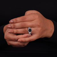 Vintage filigree statement ring featuring deep blue cabochon center stone with round accent stones and intricate scrollwork design