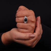 Vintage filigree statement ring featuring deep blue cabochon center stone with round accent stones and intricate scrollwork design