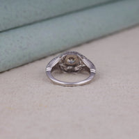 Vintage filigree engagement ring featuring a 5.00 mm round cut moissanite center stone in a decorative prong setting with intricate openwork design