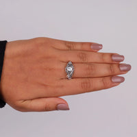 Vintage filigree engagement ring featuring a 5.00 mm round cut moissanite center stone in a decorative prong setting with intricate openwork design