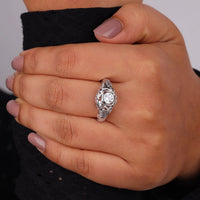 Vintage filigree engagement ring featuring a 5.00 mm round cut moissanite center stone in a decorative prong setting with intricate openwork design