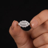 Hand holding a diamond ring against a black background