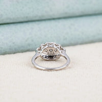 Silver ring with intricate design on a light fabric background
