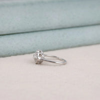 Silver ring with a diamond on a light pink surface