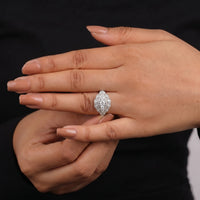 Close-up of a hand wearing a diamond ring with a black background