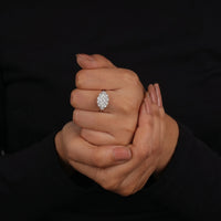 Close-up of a hand wearing a diamond ring against a black background