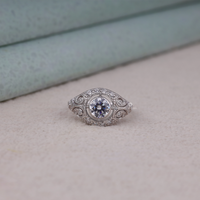 Vintage round cut moissanite bezel ring with 1.00 carat center stone, milgrain detailing, halo accents, and antique-inspired design