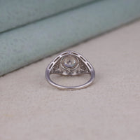Vintage round cut moissanite bezel ring with 1.00 carat center stone, milgrain detailing, halo accents, and antique-inspired design
