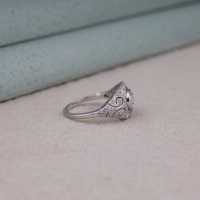 Vintage round cut moissanite bezel ring with 1.00 carat center stone, milgrain detailing, halo accents, and antique-inspired design