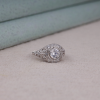 Vintage round cut moissanite bezel ring with 1.00 carat center stone, milgrain detailing, halo accents, and antique-inspired design